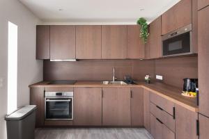 cocina con armarios de madera, fregadero y fogones en Maison moderne avec jardin12 pers proche Paris & Disney en Neuilly-sur-Marne