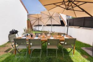 a wooden table with chairs and an umbrella at Maison moderne avec jardin12 pers proche Paris & Disney in Neuilly-sur-Marne