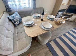a table with plates and wine glasses on top of a couch at Gannets Rest - Spacious Static Caravan with Sea Views in Polperro