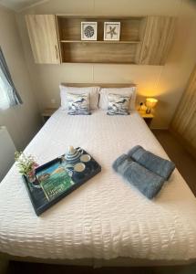 a bed with a book and a tray on it at Gannets Rest - Spacious Static Caravan with Sea Views in Polperro