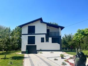 ein weißes Haus mit schwarzen Fensterläden und Bäumen in der Unterkunft Hillside Villa in Sarajevo