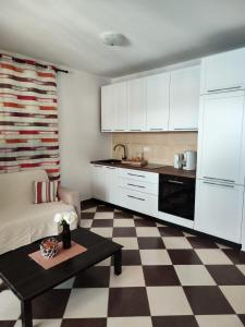 a kitchen with white cabinets and a checkered floor at Apartmani Roko in Okrug Donji