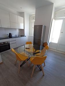 eine Küche mit einem Glastisch und gelben Stühlen in der Unterkunft FAMILY APARTAMENT II in Coimbra
