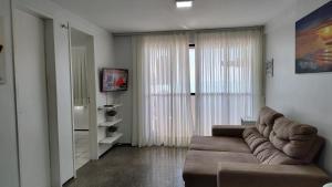 a living room with a couch and a large window at Vista espetacular 4 pessoas Praia de Iracema in Fortaleza