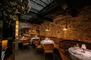 un restaurant avec des tables et des chaises blanches et un mur en briques dans l'établissement The Mercer, à New York