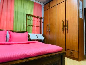a bedroom with a bed with pink sheets and wooden cabinets at ANTONIO TRANSIT KATUNAYAKE in Katunayake