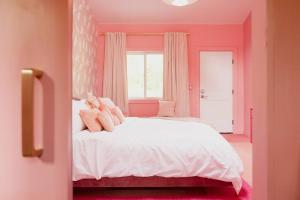 Dormitorio rosa con cama blanca y ventana en The Norsdale plus CMYK Motel on 10 acres in Phoenicia, en Phoenicia