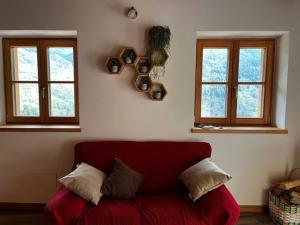 un sofá rojo en una sala de estar con 2 ventanas en Il nido al Maso Maoro, en Sant’Orsola