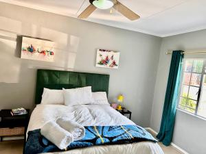 a bedroom with a bed with a green headboard at WeMukelekile (you are welcome) in Lobamba