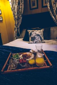a tray of food and orange juice on a bed at Sheddington Manor - 2 Bedroom Guest House & Cinema in Belfast