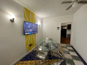 comedor con mesa de cristal y TV en la pared en OQP Vacations Edgewater, en Miami