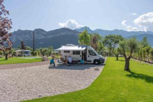 una mujer sentada en una mesa frente a un remolque en Camping Agrisalus, en Arco