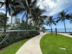 a walkway through a park with palm trees and the ocean at OQP Vacations Edgewater in Miami