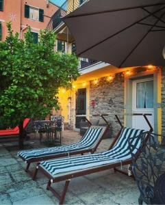 2 Liegestühle unter einem Sonnenschirm auf einer Terrasse in der Unterkunft Affittacamere Le Terrazze in Corniglia