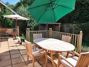 einen Holztisch und Stühle mit einem grünen Sonnenschirm in der Unterkunft Chez Ana in Saxmundham