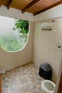 a bathroom with a toilet with a round window at Hostal Sierra Minca in Minca