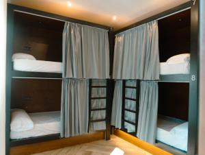 a room with three bunk beds and a ladder at La Banda Rooftop Hostel in Seville +75 photos