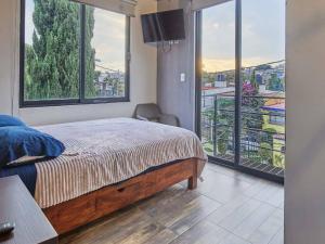 ein Schlafzimmer mit einem Bett und einem großen Fenster in der Unterkunft R77 Habitación de Lujo Totalmente Equipada in Mexiko-Stadt