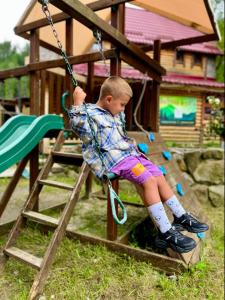 a young boy sitting on a swing in a playground at Girskiy Prutets in Bukovel