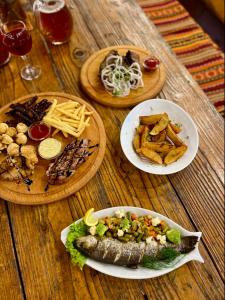 a wooden table with plates of food with fish and french fries at Girskiy Prutets in Bukovel