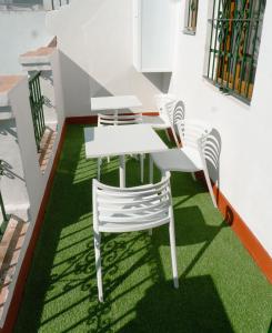 una mesa y sillas en un piso con césped en La Banda Rooftop Hostel, en Sevilla