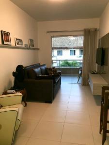 a living room with a black couch and a large window at Residencial Verano in Guarajuba