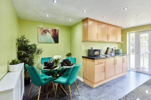 uma cozinha com paredes verdes e uma mesa e cadeiras em *Little Haven in Leeds* ¤Private Parking¤ Ensuite em Killingbeck