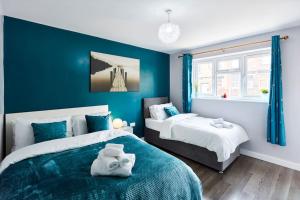 Duas camas num quarto com paredes azuis em *Little Haven in Leeds* ¤Private Parking¤ Ensuite em Killingbeck