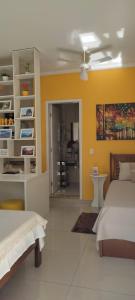 - une chambre avec 2 lits et un mur jaune dans l'établissement Hospedagem Quarto Chic centro Cunha, à Cunha