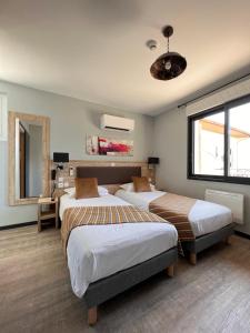 een slaapkamer met 2 bedden en een groot raam bij Hôtel La Pinède in Soulac-sur-Mer
