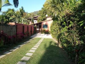 a garden with a pathway leading to a house at Casa com Piscina a 100 m. de Camburizinho in Camburi