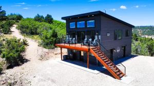 ein schwarzes Haus mit einer Holzterrasse und einer Treppe in der Unterkunft Bryce View Cabin - New Cabin With Amazing Views! in Alton