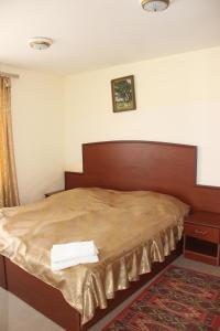 - une chambre avec un grand lit et une tête de lit en bois dans l'établissement Hotel Lori Berd, à Stepanavan