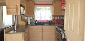 a small kitchen with a sink and a stove at 2 bed pet friendly caravan at Hoburne Devon Bay with decking in Paignton