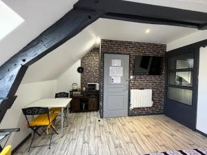 Pokój ze stołem, drzwiami i ceglaną ścianą w obiekcie Chambres d'hôtes à la forge du Coglais w mieście La Selle-en-Coglès