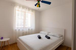 a white bedroom with a bed with a ceiling fan at Villa Andrea in Koper