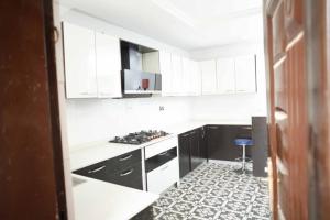 kuchnia z białymi szafkami oraz czarno-białą podłogą wyłożoną kafelkami w obiekcie DMK Shared Apartments w mieście Abudża