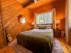 ein Schlafzimmer mit einem Bett und einer Gitarre in einem Zimmer in der Unterkunft Runway Cabin Retreat With Private Hot Tub! in Duck Creek Village