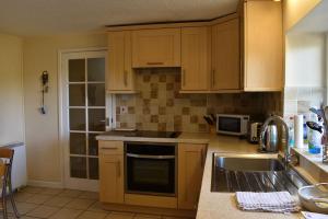 a kitchen with wooden cabinets and a sink at Holly Lodge in Bramerton