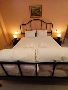 um quarto com uma cama grande com lençóis brancos e almofadas em Apartment Rustico em Ancient Epidavros