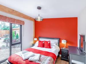 sypialnia z czerwonymi ścianami i łóżkiem z czerwonymi poduszkami w obiekcie Fioled - Uk40267 w mieście Llangadfan
