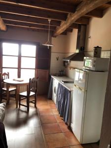 een keuken met een tafel, een fornuis en een koelkast bij Apartamentos Rurales CASONA DE LOLO in Caunedo