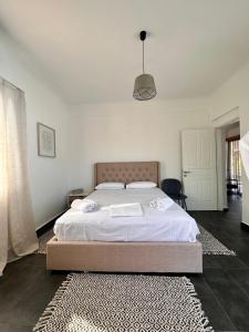 a bedroom with a large bed with white sheets and a rug at Orange Grove Nafpaktos in Nafpaktos
