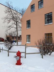 a red fire hydrant in the snow in front of a building at Beautiful apartment in the heart of Reykjavik in Reykjavík
