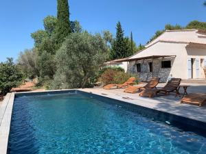 a swimming pool with chairs and a house at Lodge de charme 135m2 avec piscine dans les vignes AOC Bandol à 15 min des plages et du circuit Paul Ricard F1 in Le Beausset