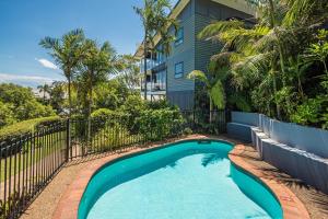 ein Pool vor einem Haus mit einem Zaun in der Unterkunft Escape to Paradise at Oasis 1, a 2BR Central Hamilton Island Apartment with Buggy! in Hamilton Island