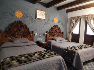 a bedroom with two beds and two windows at Hotel Grand Maria in San Crist&oacute;bal de Las Casas