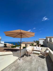 eine Terrasse mit Sonnenschirm, Stühlen und einer Couch in der Unterkunft Luminosa villa con vistas al mar en Cala Moraig in Benitatxell