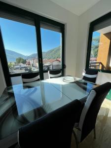 a dining room table with chairs and a large window at Apartman Paradise Fojnica in Fojnica