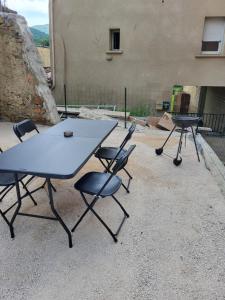 trzy stoły piknikowe i krzesła przed budynkiem w obiekcie La Grange - 10 couchages w mieście Carla-de-Roquefort